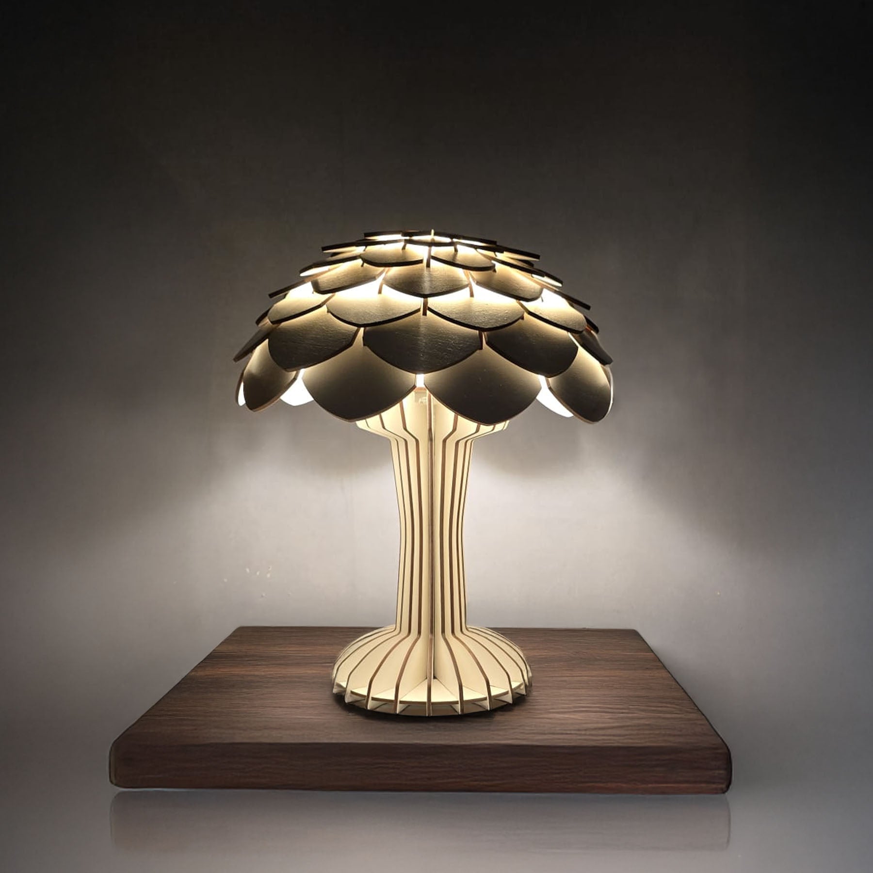 A table lamp with a nature-inspired design, featuring a birch veneer structure resembling a tree and a mushroom, emitting warm light.
