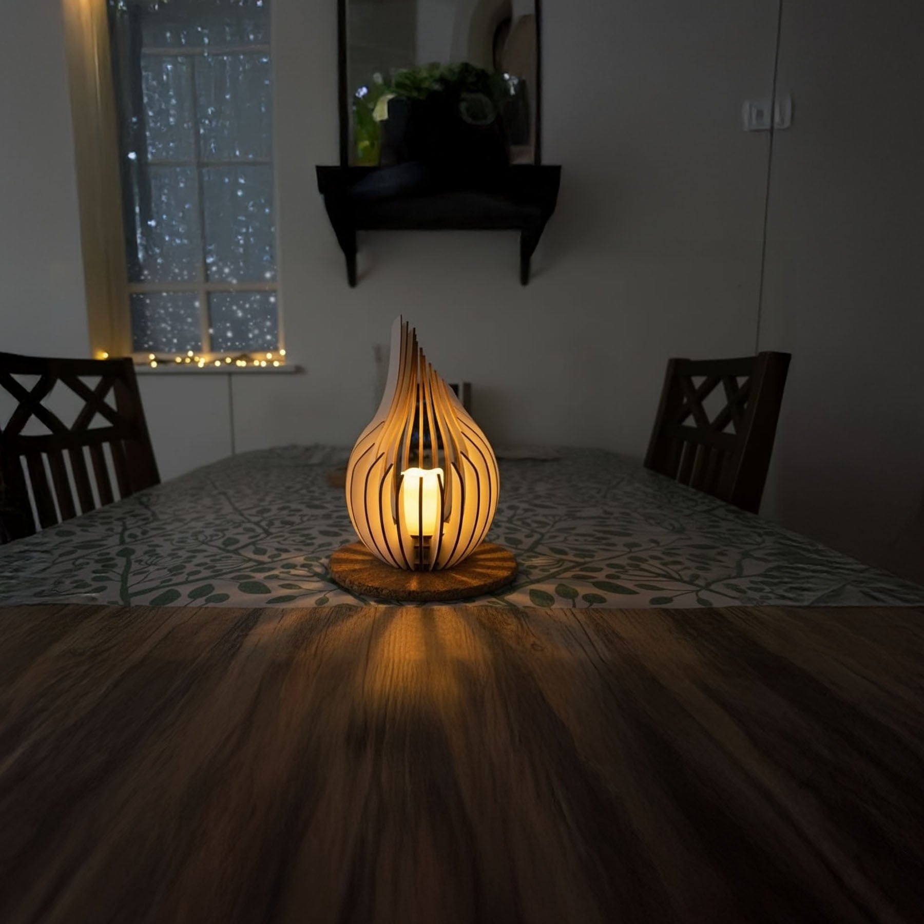 Wooden lamp on a table with a window showing city lights in the background