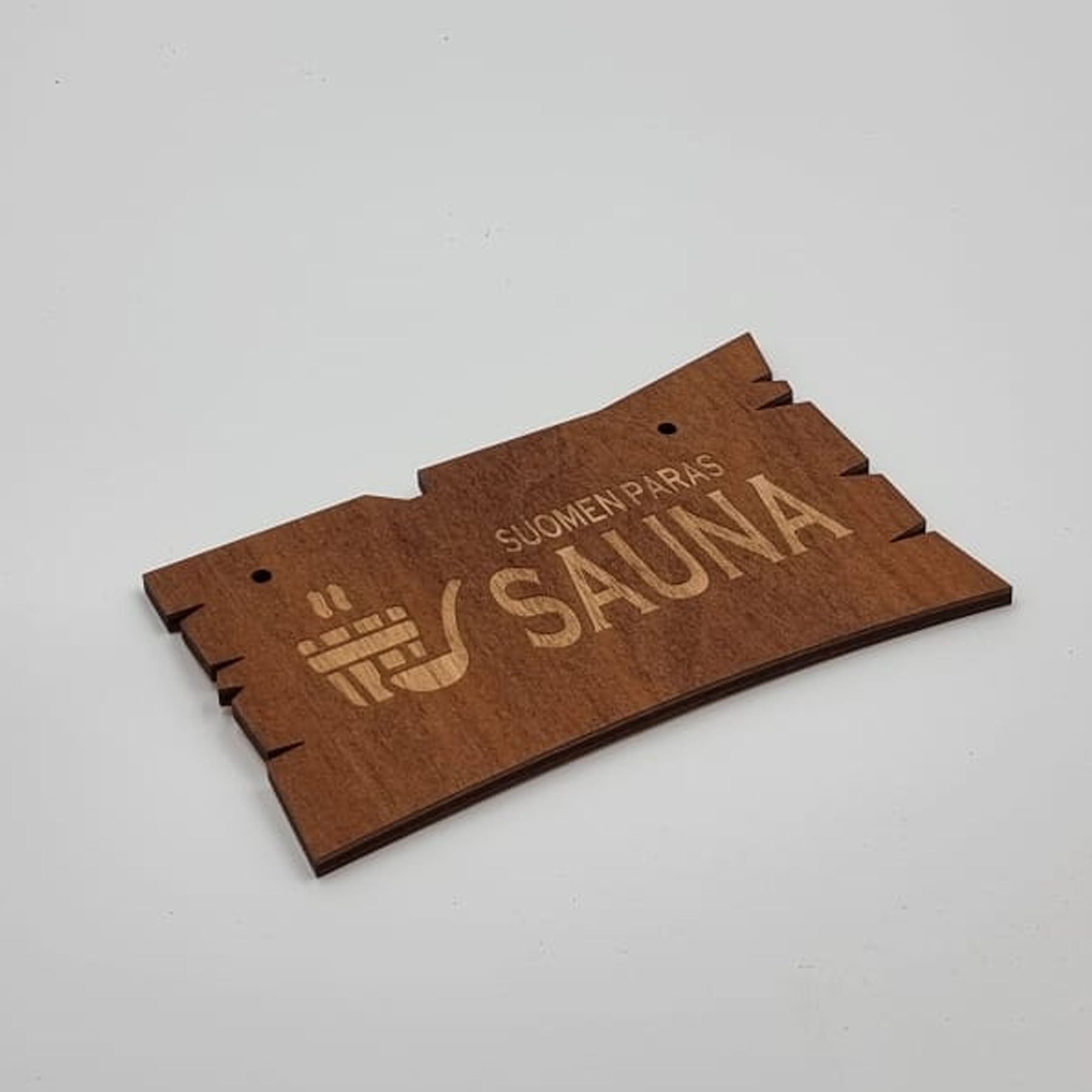 A wooden sauna sign with laser-engraved text and traditional sauna imagery, on a white background.