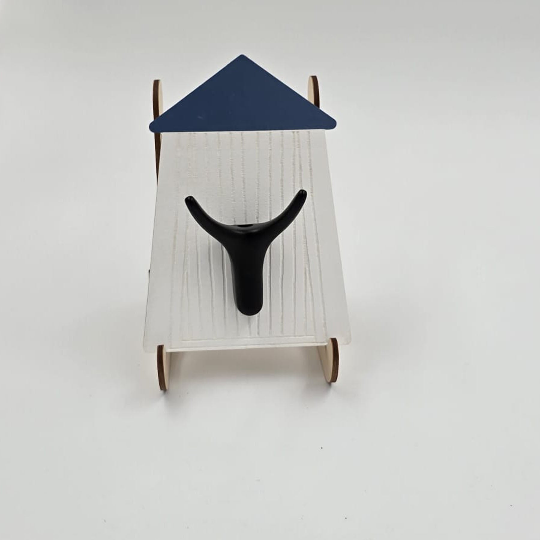 A wall hook with a white background designed to resemble a coastal bathroom scene, with a dark brown hook and a navy blue roof.