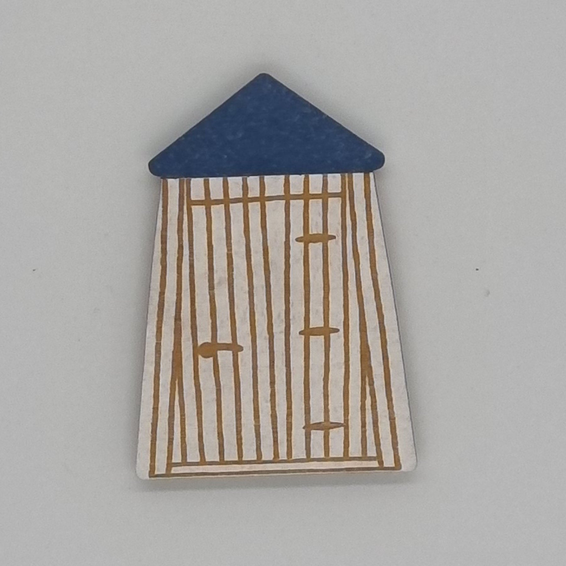 A handcrafted magnet depicting a bathing room with vertical wooden slats and a blue roof.